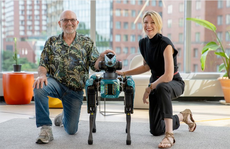marc raibet and kate darling kneel next to a boston dynamics spot robot.